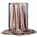 Dettaglio del foulard in raso color champagne a pois neri appeso su un supporto - Cachi a Pois