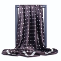 Gros plan d'un foulard en satin marron à pois blancs drapé sur un support noir - Café à Pois