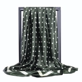Détail d'un foulard en soie vert foncé à pois blancs avec finition satinée brillante - Vert olive