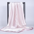 Dettaglio del foulard in raso a righe perlate drappeggiato su un supporto in metallo minimalista - Rosa Chiaro