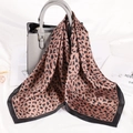 Fashionable leopard print silk scarf draped over a grey leather handbag for stylish look - Coffee