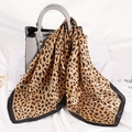 Fashionable leopard print silk scarf draped over a grey leather handbag on a soft background - Brown Leopard