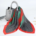 Green and red striped satin square scarf draped on a textured grey leather handbag - Red