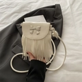 Creamy white crossbody bag with silver bow and fringe tassels on a textured surface - White
