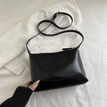 Chic black tote bag in glossy synthetic leather with adjustable strap for daily commute - Black