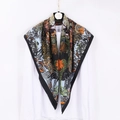 Black square silk scarf featuring vibrant tropical floral and bird print hanging on shirt - Jungle Black Border
