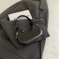 Bolso hobo media luna de charol negro minimalista con detalles dorados en blazer gris - Negro