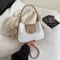 White woven crescent bag with khaki leather flap and gold twist lock in hand - White