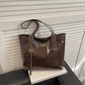 Bolso tote marrón café brillante con etiqueta de moda sobre libro blanco y fondo de sofá de cuero - Marrón