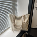 Minimalist beige glossy leather tote bag with long handles in soft natural window light - White