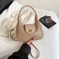 Brown woven crescent bag with round handle and gold hardware shown on a white bed - Khaki