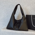 Minimalist black soft leather tote bag with wide shoulder strap on stone display - Black