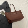 Dunkelbraune Leder-Shopper-Tasche mit goldenen Beschlägen auf weißem Stoff - Braun