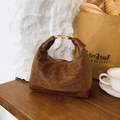 Braune Hobo-Tasche mit Leopardenmuster aus Wildleder auf einem rustikalen Holztisch - Braun