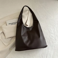 Minimalistische donkerbruine lederen shopper met hobo-ontwerp in een moderne lifestyle-omgeving - Bruin