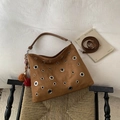 Close-up of brown suede hobo bag featuring large silver metal eyelets and plush charm - Brown (With Pendant)