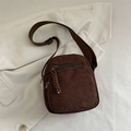 Brown corduroy crossbody bag with adjustable strap and woven zipper pulls on white shirt - Brown