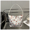 Gros plan du sac fourre-tout en toile blanche avec motifs cerises rouges sur une chaise - Blanc