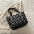 Quilted black puffer tote bag with wide ethnic pattern strap on a beige fabric background - Black