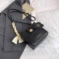 Chic black bucket bag with silk scarf handle and metal clasp on textured background - Black