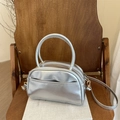 Borsa a mano argento metallizzato a forma di cuscino con manici e tracolla su una sedia - Argento