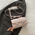 Sac cylindrique rose avec fermoir rotatif argenté et bandoulière sur veste grise - Rose