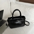 Bolso de mano negro brillante con hebilla de cinturón y herrajes plateados en cama - Negro