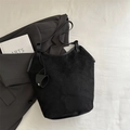 Minimalistische schwarze Wildleder-Einkaufstasche mit Herzanhänger auf hellem Stoff - Schwarz