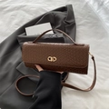 Brown woven texture handbag with gold buckle on white bedding and grey suit backdrop - Brown