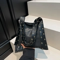 Bolso de hombro en PU negro con ojales dorados y correas anchas en fondo moderno - Negro