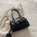 Black balletcore PU leather shoulder bag with bow details on a beige blazer background - Black