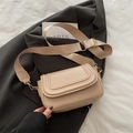 Apricot saddle crossbody bag with wide fabric strap and golden hardware on grey fabric - Khaki