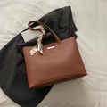 Brown leather tote bag with fashion lettering and floral scarf accent on black blazer - Brown