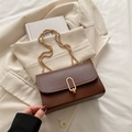 Brown leather crossbody bag with gold oval clasp and chain strap on beige blazer - Brown