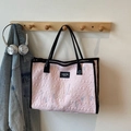Pink quilted tote bag with black handles and colorful embroidery in a lifestyle setting - Pink