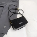 Detailed top view of a black crossbody bag showing textured leather on a grey blazer - Black