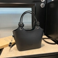 Schlichte schwarze Beuteltasche mit Knotengriffen und abnehmbarem Schultergurt auf Marmor - Schwarz