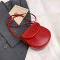 Classic red saddle crossbody bag in glossy leather shown with dark grey blazer and cafe card - Red
