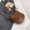 Dark brown faux leather saddle bag with adjustable strap on aesthetic background - Brown