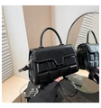 Detail of black minimalist handbag showing 3D cube embossed texture and curved handle - Black