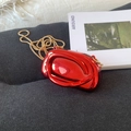 Mini borsa rossa metallizzata di lusso con catena dorata su sfondo in tessuto grigio - Rosso
