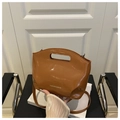 Detail of glossy brown patent leather bucket bag with silver lettering and cutout handle - Brown
