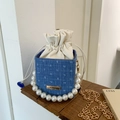 Blaue Denim-Perlenhandtasche mit goldener Kette auf einem rustikalen Holzsockel - Blau