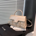 Elegante borsa crema con trama a quadri e patta irregolare su un abito nero e libri - Cachi