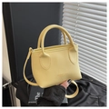 Dettaglio borsa a mano gialla in pelle martellata con marchio impresso e texture fine - Giallo
