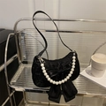 Elegant black crescent shoulder bag with a large bow and pearl chain on a stylish shelf - Black