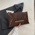 Dark brown snakeskin envelope clutch with gold metal trim on a grey suit background - Brown