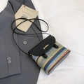Rainbow woven crossbody bag with black flap and gold logo on white fabric backdrop - Black