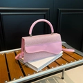 Bolso bandolera rosa con solapa ondulada y asa redonda en banco de madera - Rosa