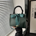 Sac bandoulière vert foncé avec nœud et poignée tissée dans un décor minimaliste - Vert